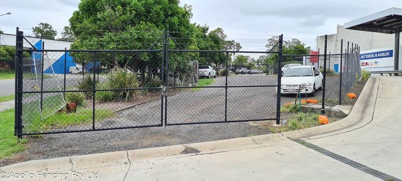 Commercial Fencing in Yatala installed by Apollo Fencing with black PVC coated chain wire, barbed wire and a set of double security gates