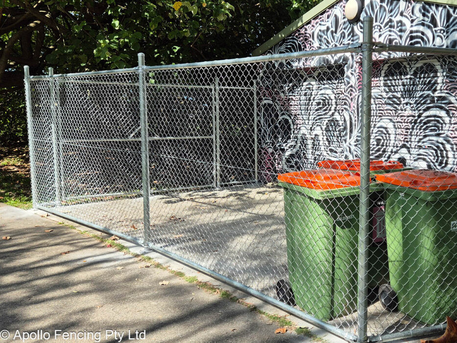 Outdoor storage enclosure in Coolangatta on the Gold Coast built with galvanised chain wire, providing a secured area next to a public mural wall and garden space. Designed and installed by Apollo Fencing