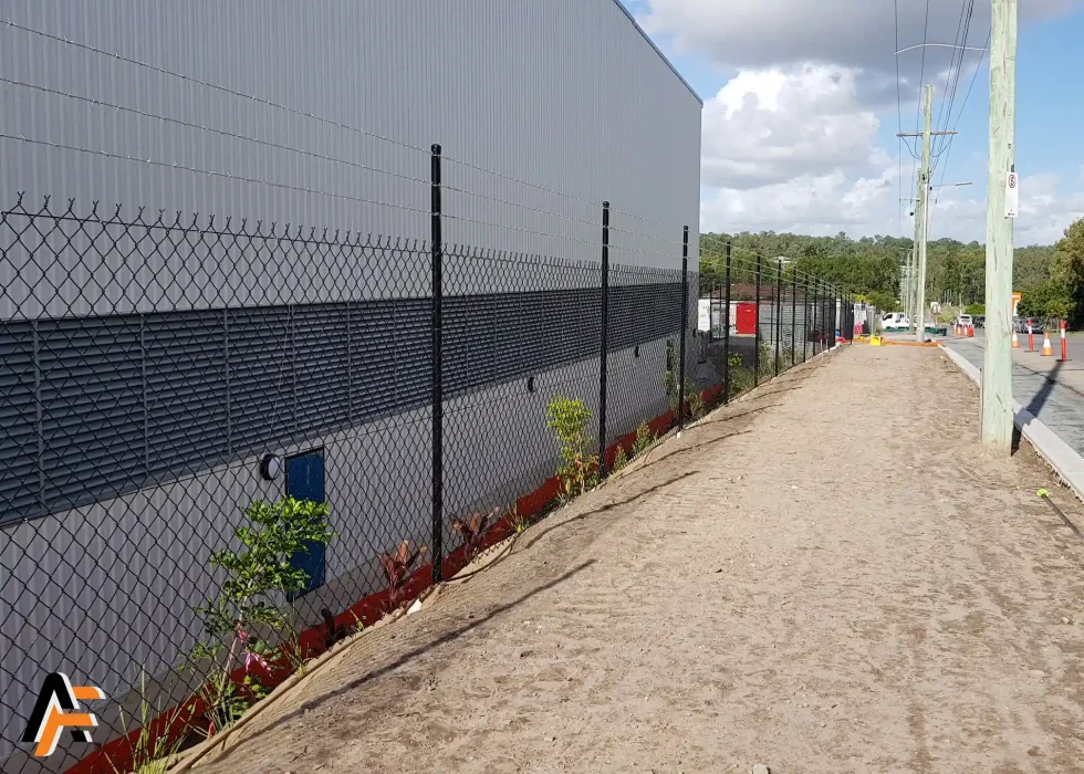 Chain wire security fencing installed along the side of a commercial building in Brisbane, providing durable perimeter protection with a clean boundary line.
