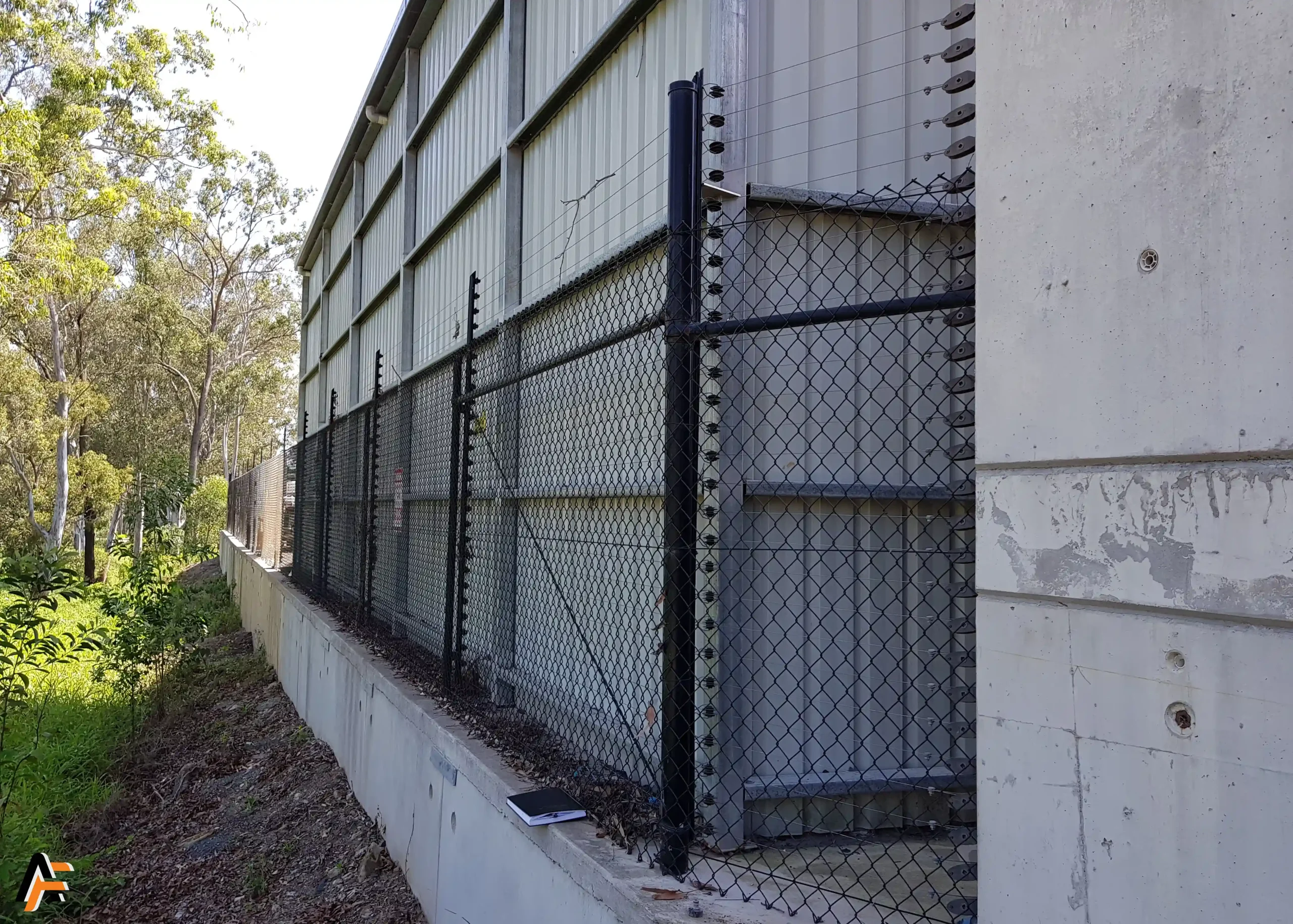 Chain wire security fencing with electric deterrent wires installed alongside an industrial building in Brisbane for perimeter safety.